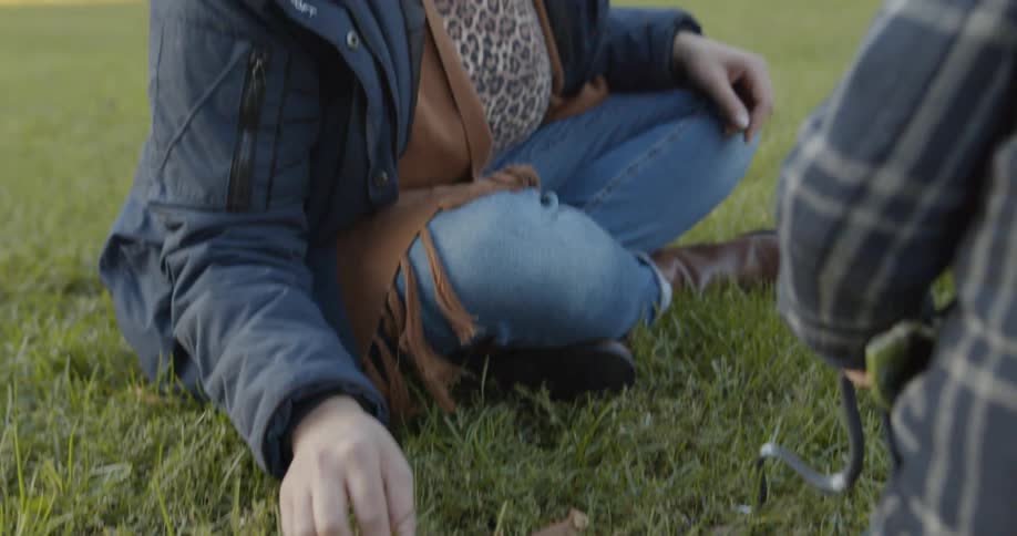 A mother and daughter play with a toy horse and toy snake on a lawn at low sun