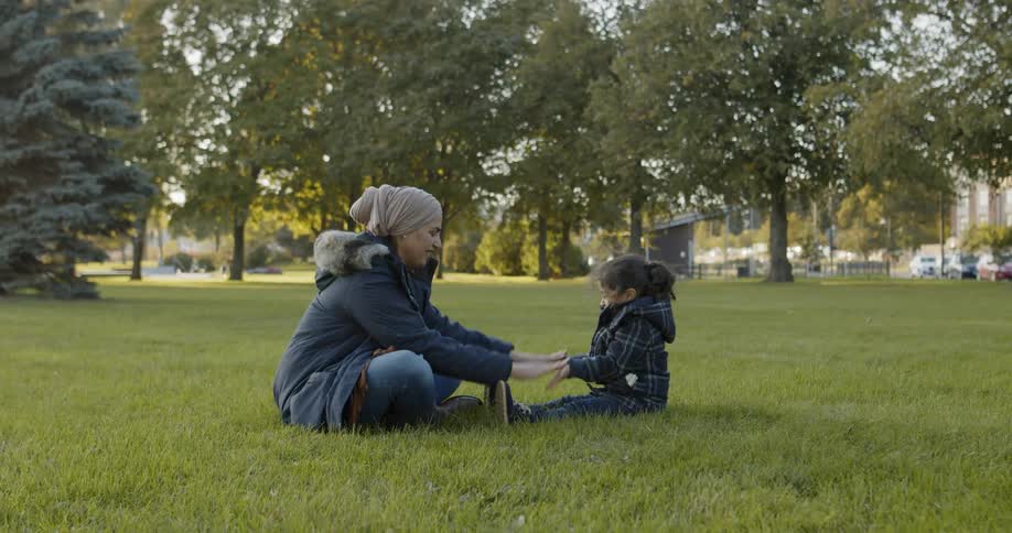 Woman plays with toddler on the grass field in the daytime