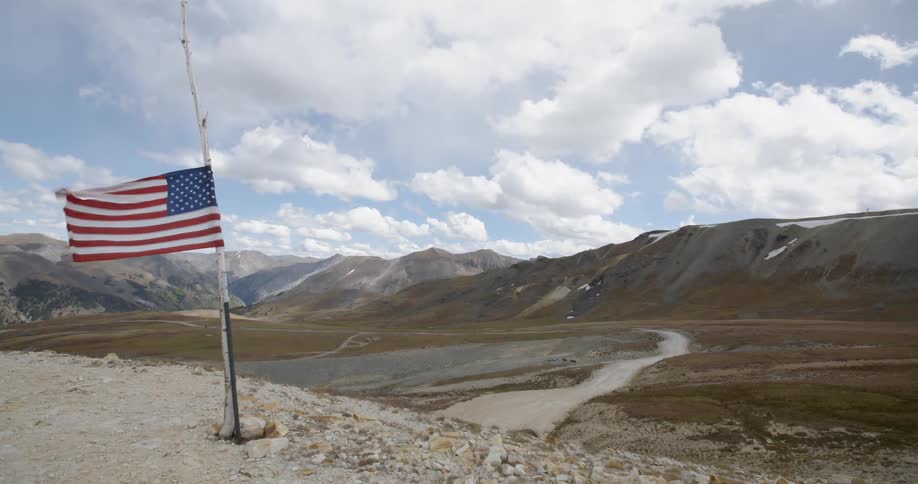 An american flag at half mast waving in a valley