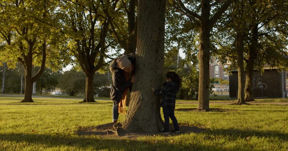 A woman plays peek a boo with a child in a park