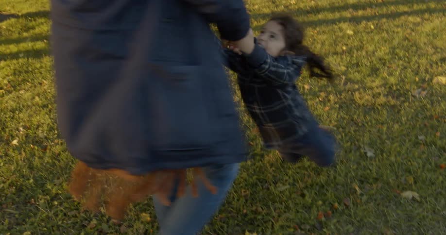 Mother spinning her daughter in the air at a public park