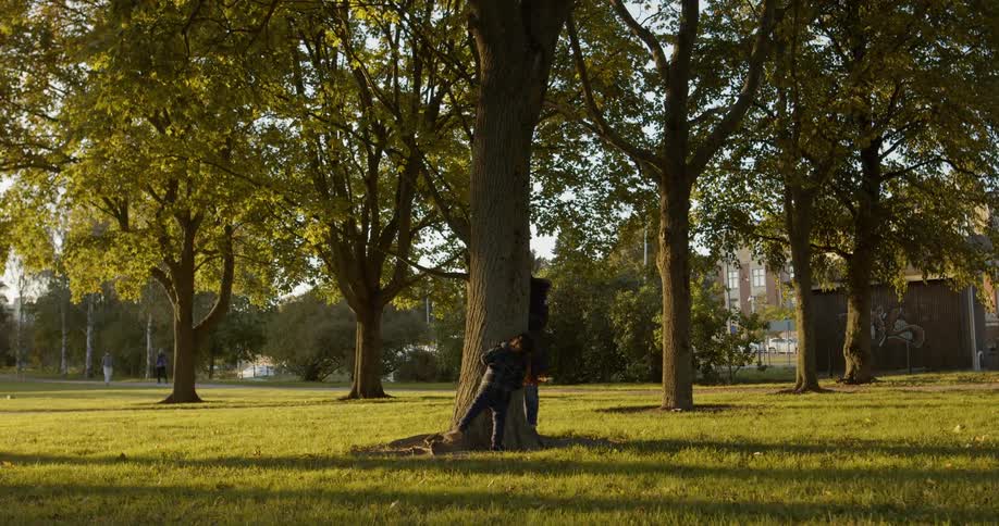Mother and daughter playing on a public park around a big tree