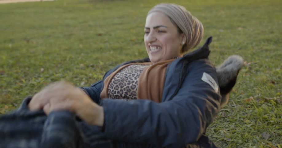 A woman plays with a child on the grass