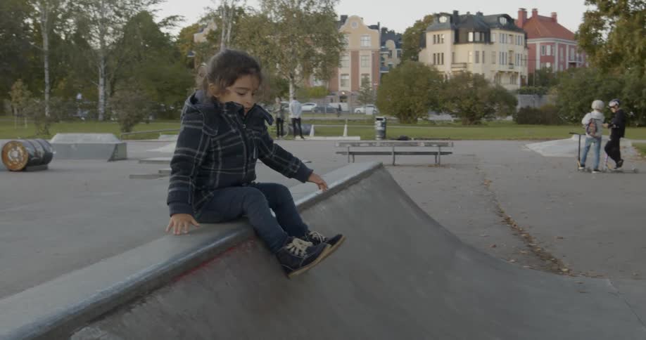 A child slides down a ramp at a skatepark