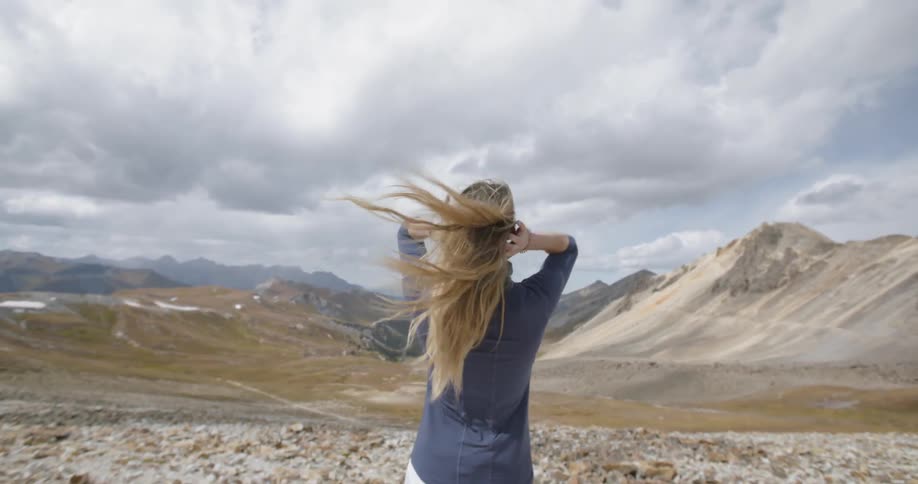 Woman walks on the rocky plane towards mountains on the horizon