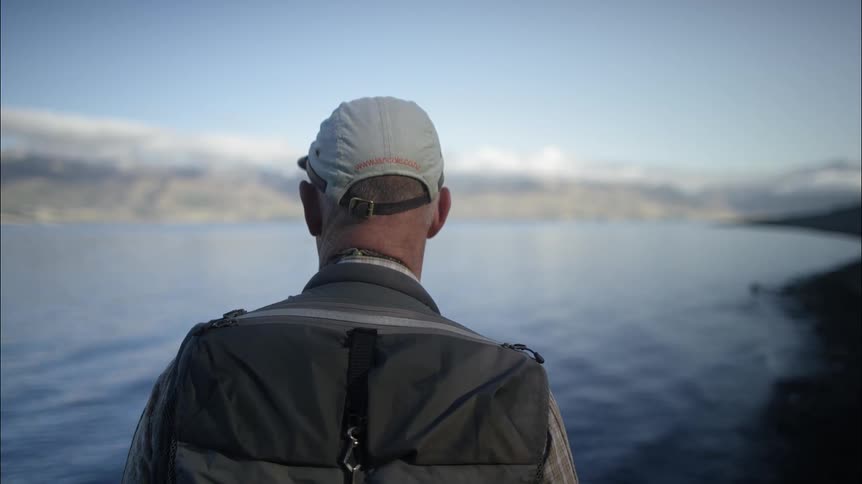 A fisherman overlooking a rippling lake