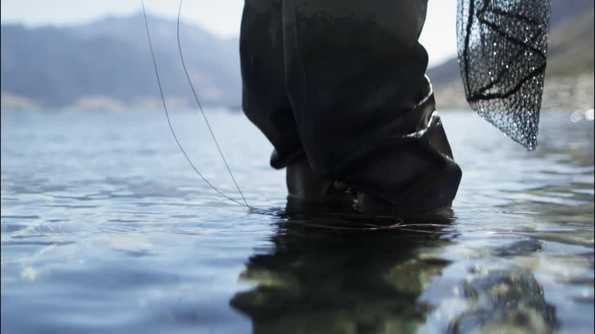 A man is fishing in a stream