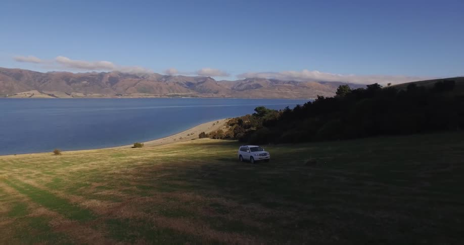 An suv drives up a shoreline grass hill