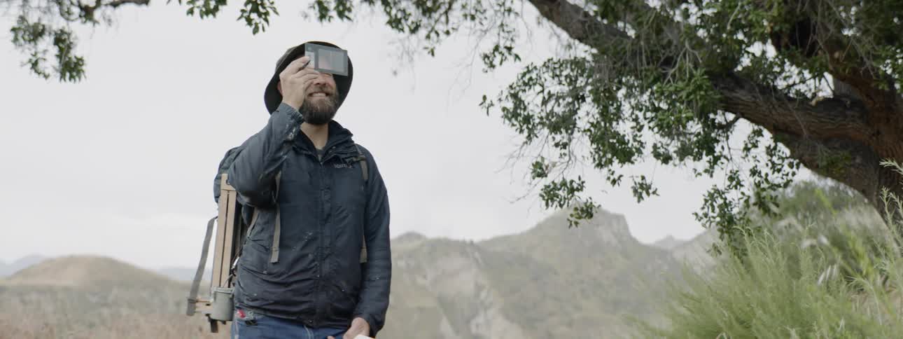 A man holding a paper to his face in the forest