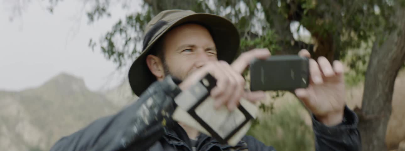 A white man takes an outdoor picture with his smartphone