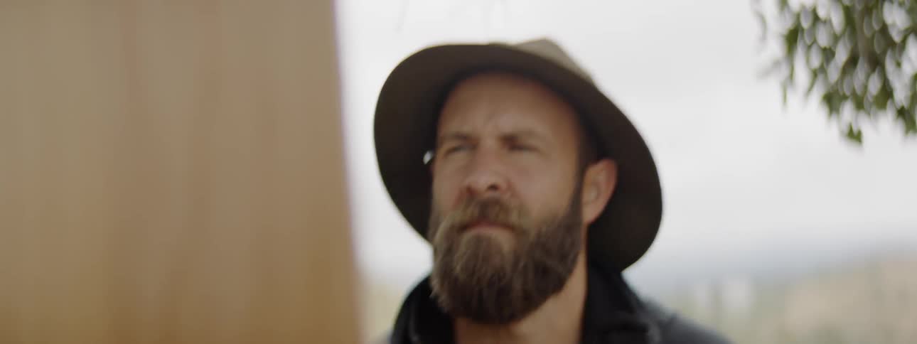 A man backs up to look at his painting