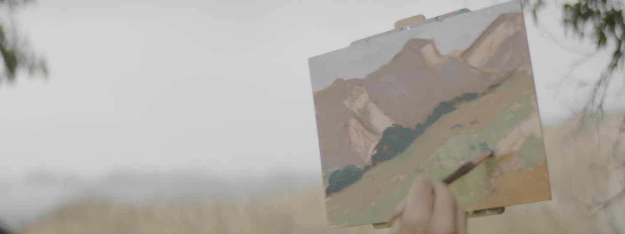 A white man paints a picture outdoors
