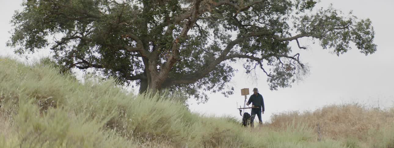 A man standing on top of a hill with a machine