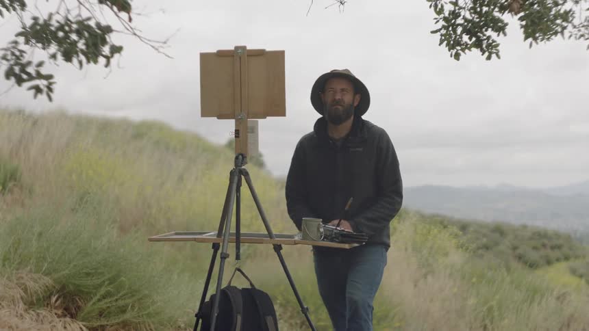 Man steps back from his painting to look at the scenery