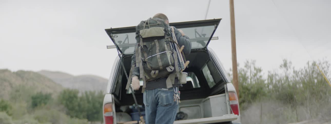 A man taking a backpack out of a truck
