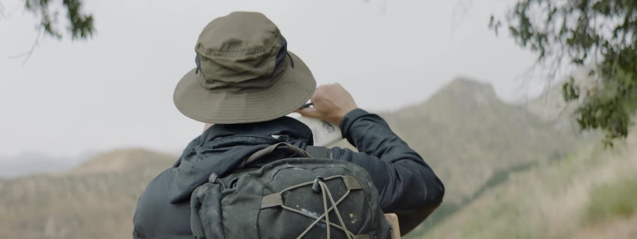 Man looks out across a valley framing the landscape with his fingers