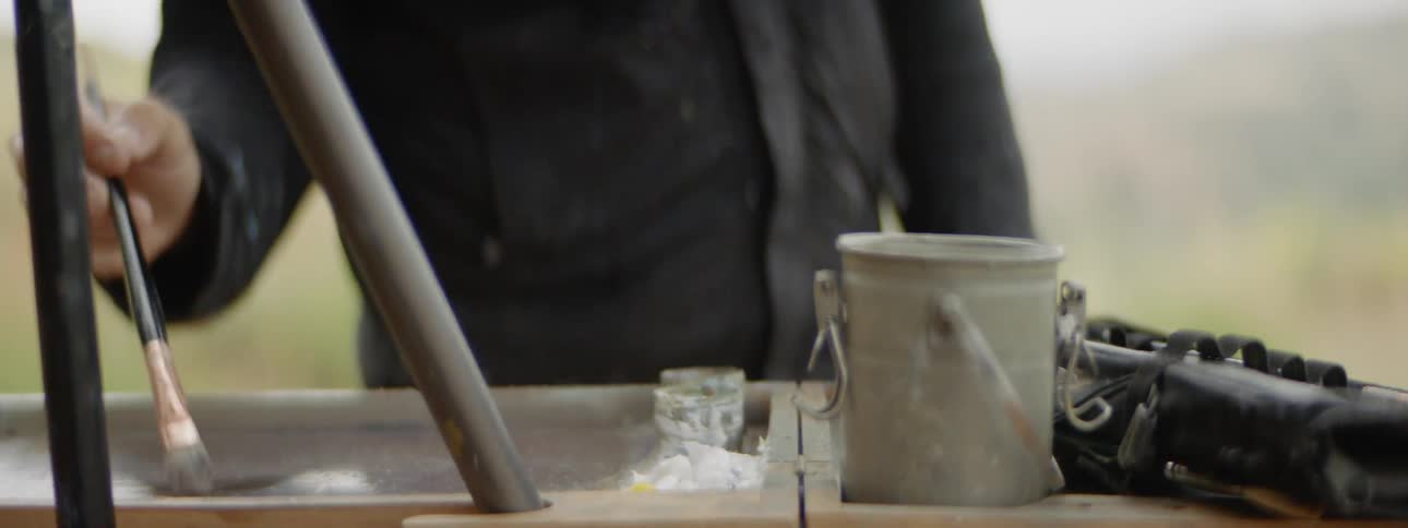 Painter dipping paint brush in paint can and removing excess paint off