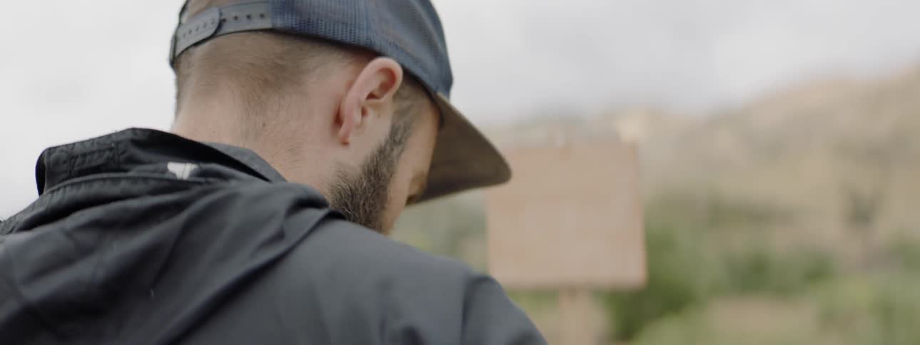 A man in a cap gets something from his pockets in a rural area