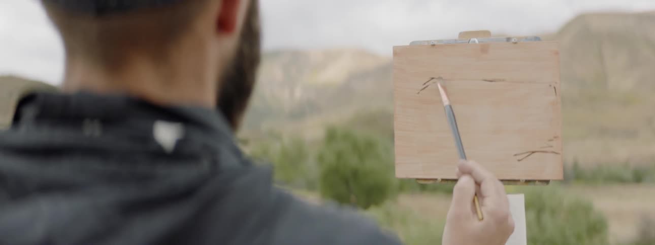Bearded white man draws a frame in the nature on a cloudy day