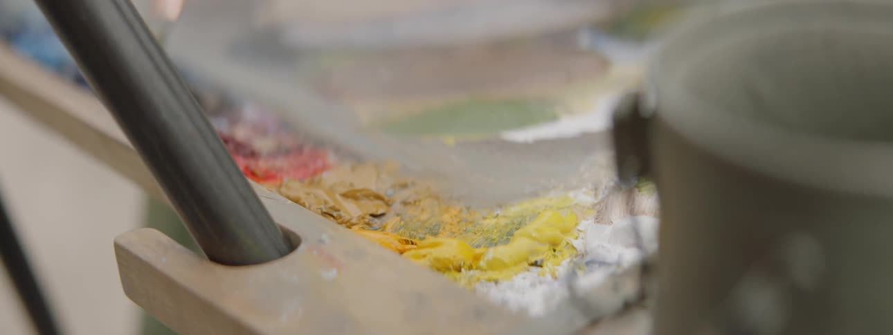 A paintbrush is dipped in to yellow paint