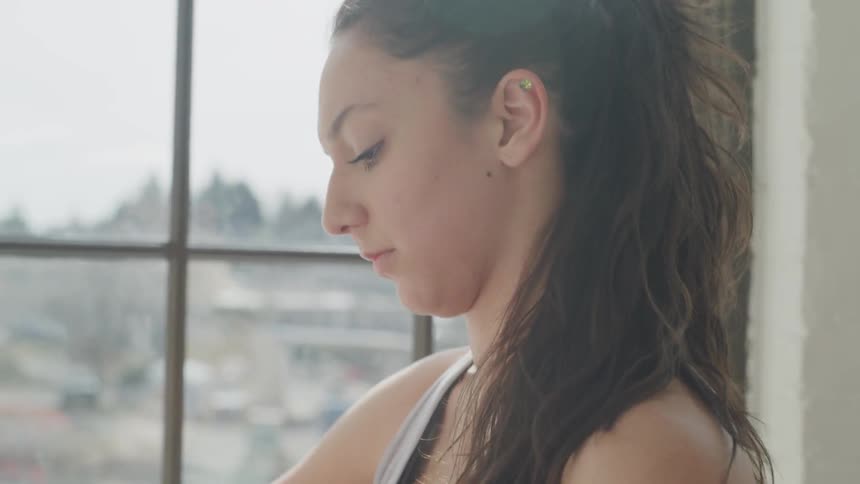 A woman standing next to a window putting on a hand wrap
