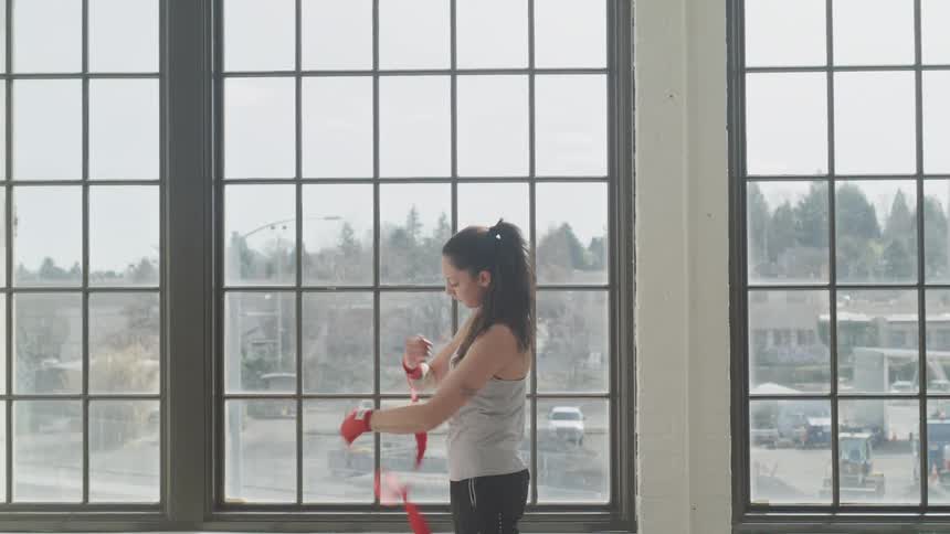 A woman with a boxing glove on puts tape on her arm