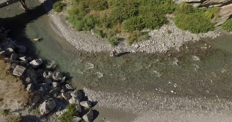 Aerial of a person walking across a stream