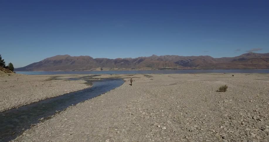 Backpacker walking on rocky terrain along a waterway