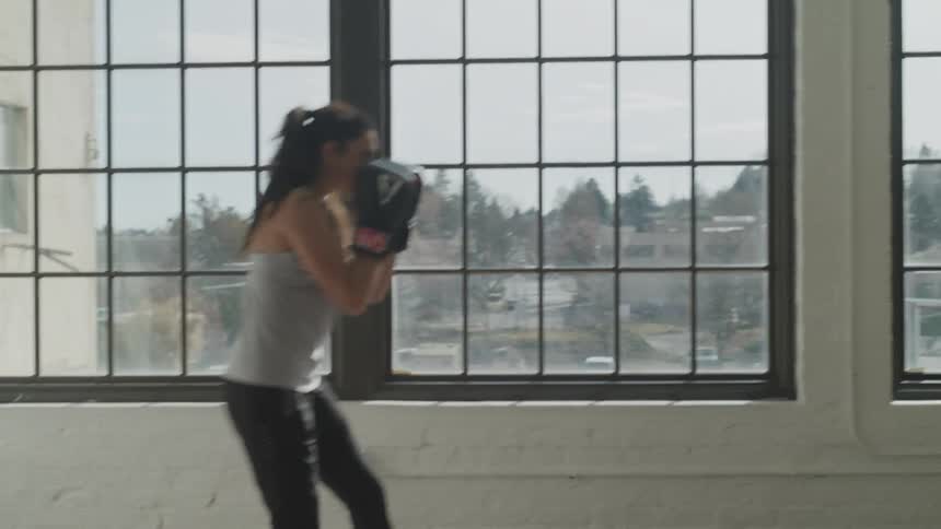 Woman boxing in front of window with the landscape of town on a sunny day