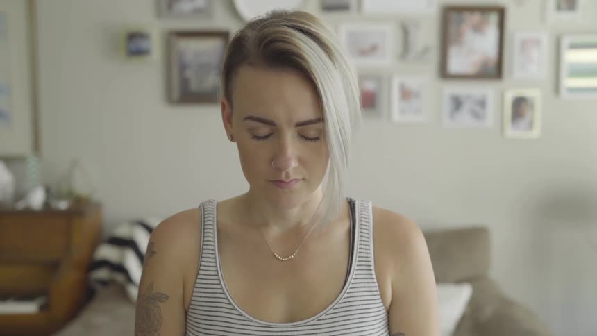 A woman sits in a room with her eyes closed