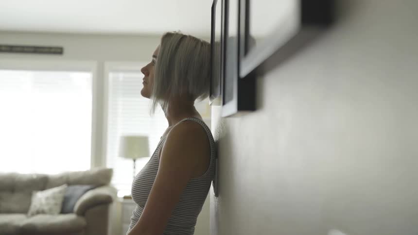 A woman standing inside with her back against the wall