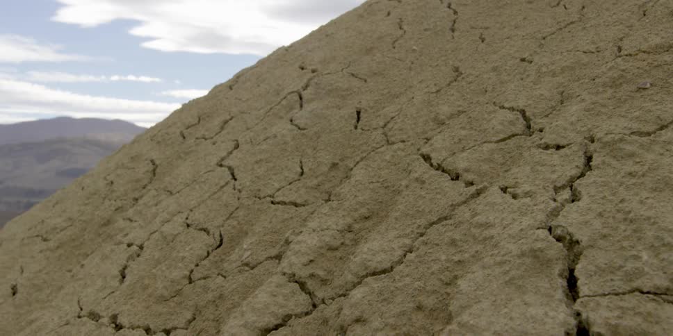 Cracks form in dry dirt at the peak of a cliff