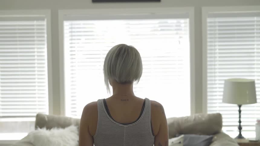 A woman stands in a living room looking around