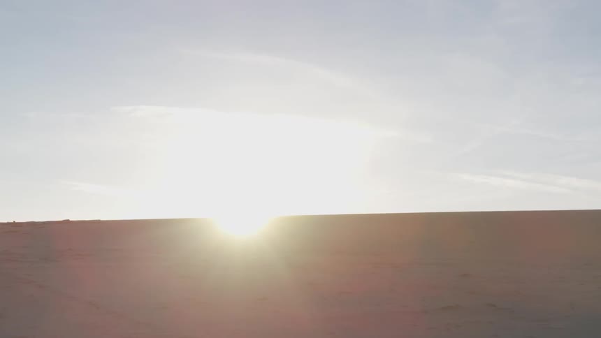 A desert with the sun and sky in the background