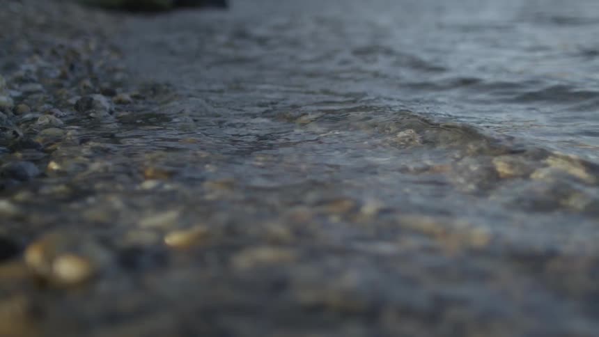 Water is hitting the shore with many rocks on it