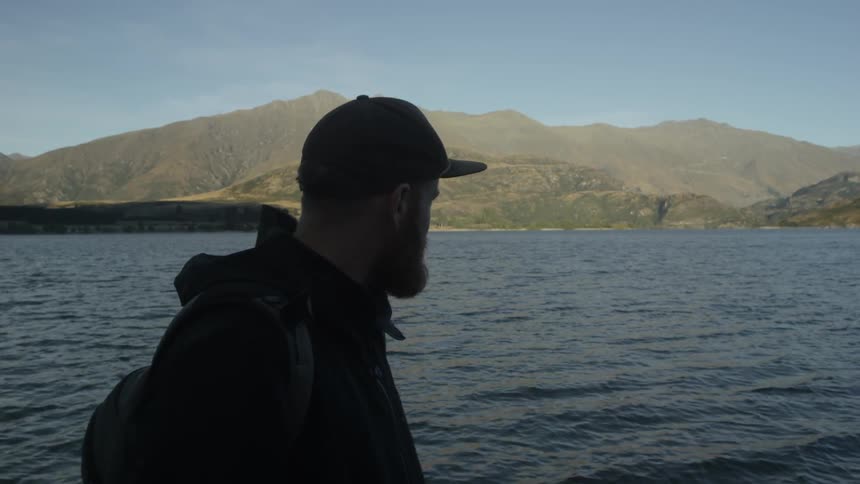 Man walks next to a mountain lake