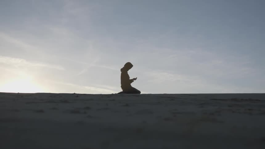 A woman kneeling looking at her hands