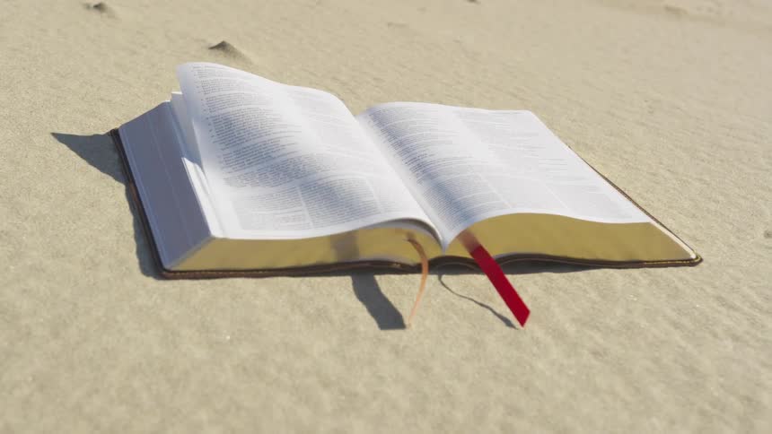 Pages of the bible gently in the breeze on the beach