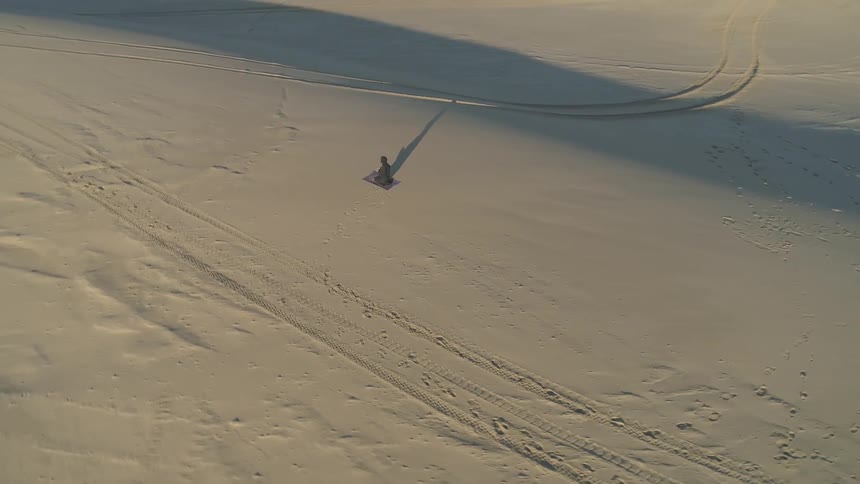 A person meditates on a carpet in a desert at daytime