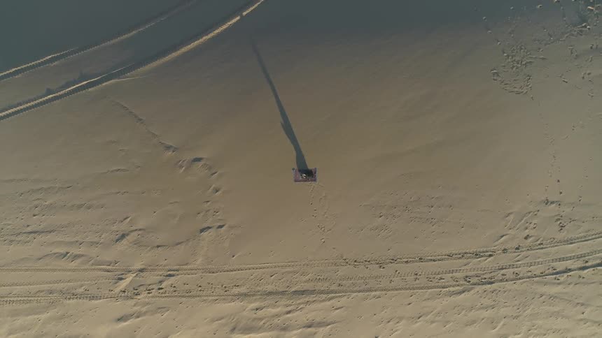 Aerial view of a person lying on a mat on a quiet beach