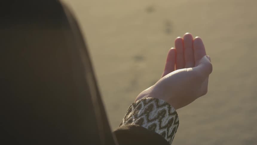 A person outside hand open in prayer