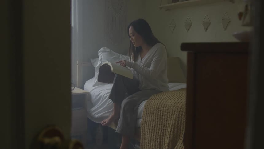 A woman sitting on a bed reading a book