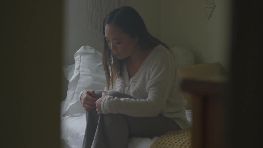 A woman holding her legs while sitting on a bed