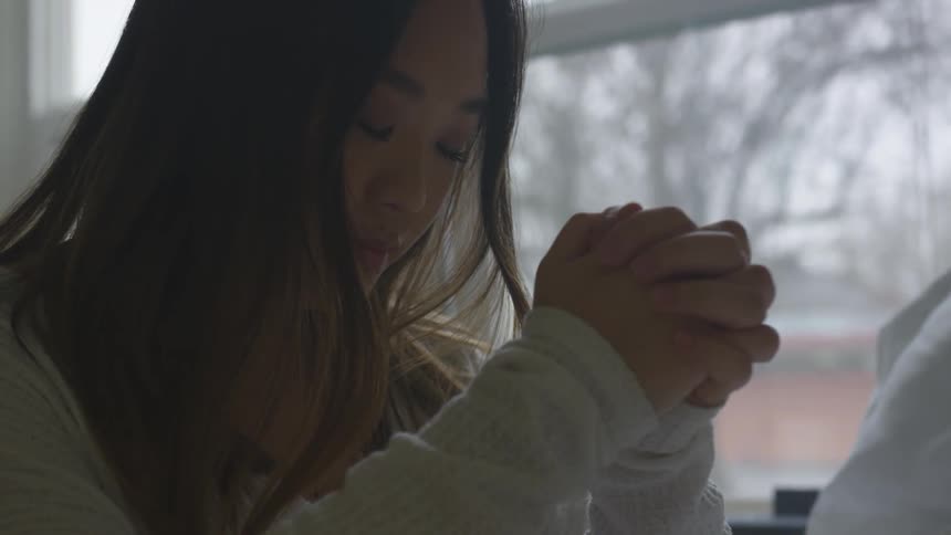 A young girl sits and prays