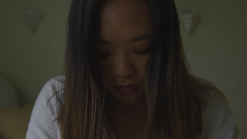 A woman is indoors in a room closing her eyes