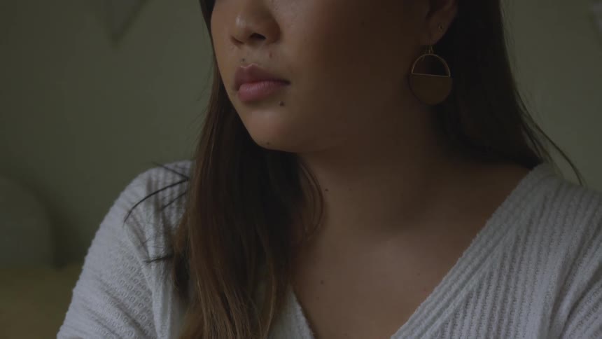A brunette woman sits in a room and stares