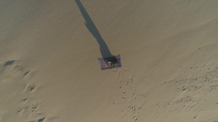 Birds eye view of a person lying on a mat on a beach