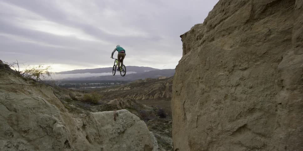 A man doing a jump on his bike across a large cliff