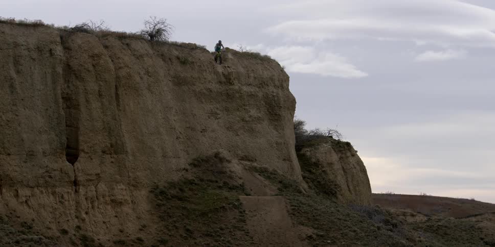 A bmx rider stops to overlook a steep cliff