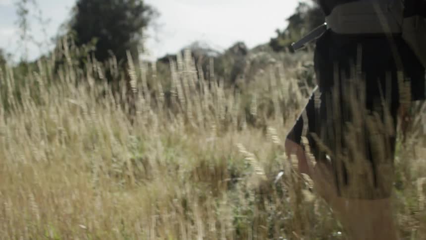 Hiker walks through a grassy field on a sunny day